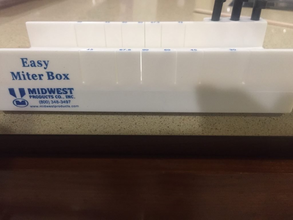 A picture of the front of the miter box hanging off the edge of the counter.