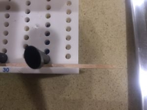 A top view of the miter box set up with the balsa wood hanging out of the edge